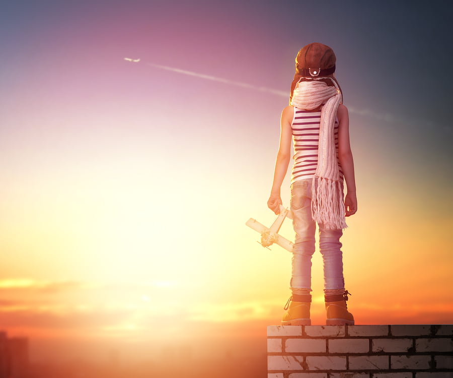 Child dressed as a pilot staring at a plane